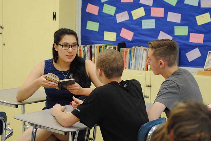 Houghton education major student teaching with book.