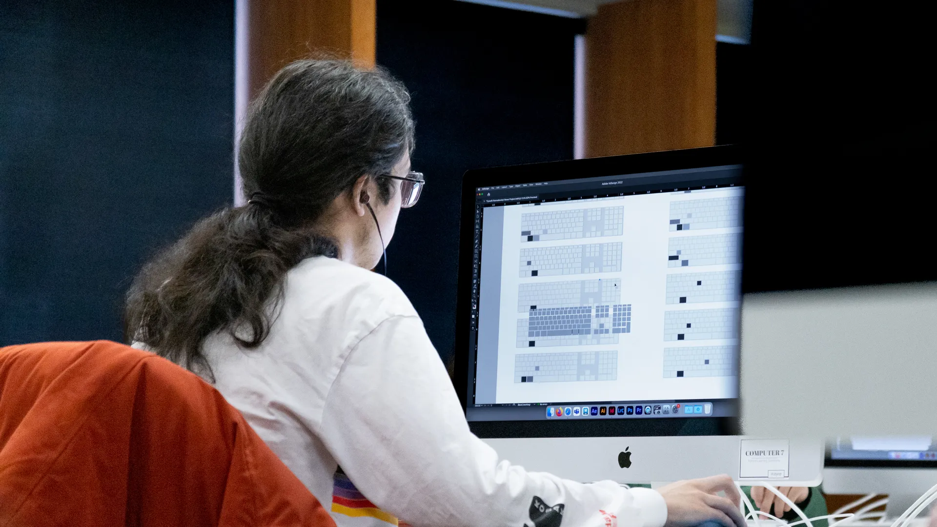 Houghton graphic design student sitting at computer in mac lab.