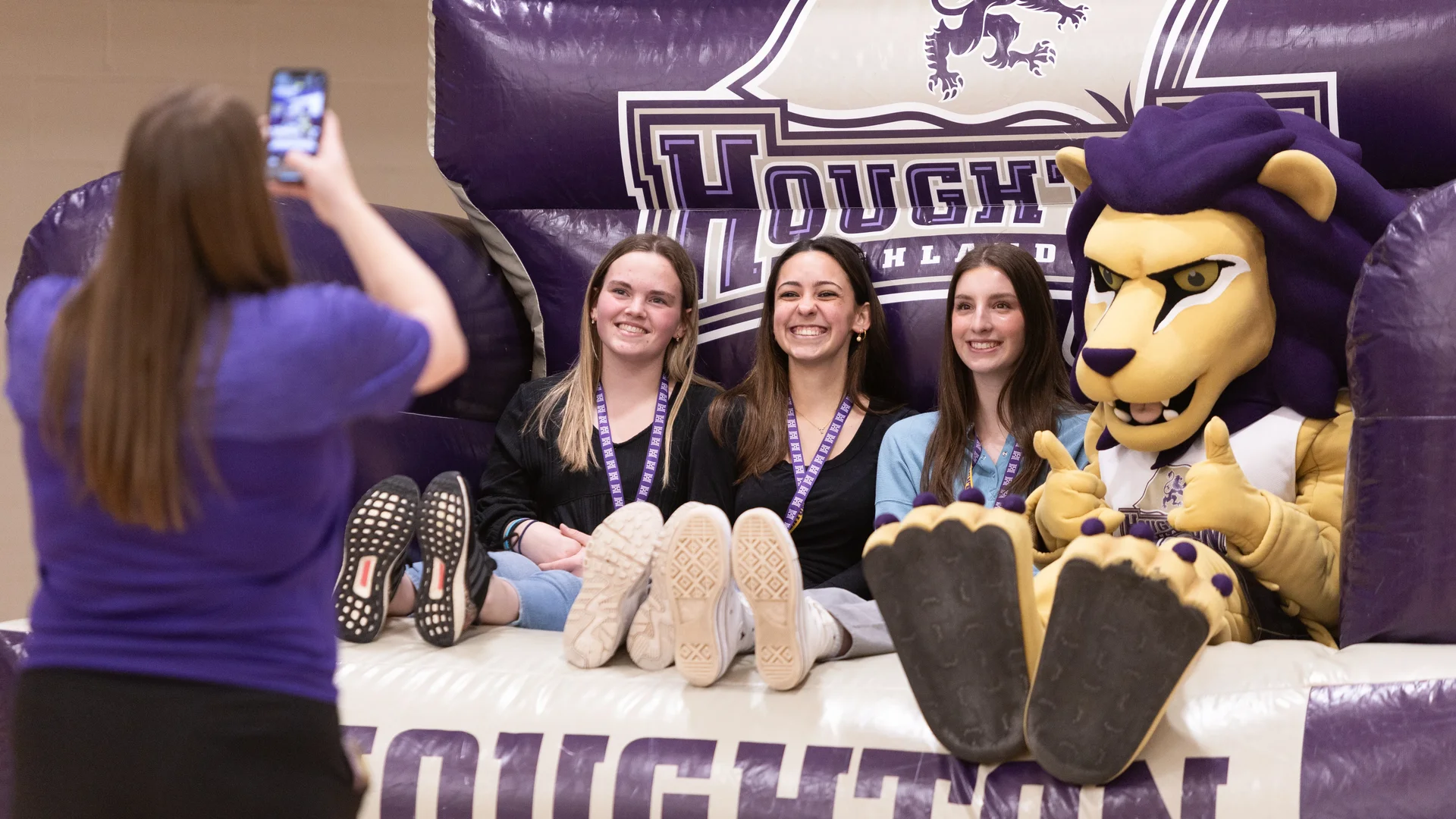 Three accepted student sitting on huge inflatable chair with mascot Luckey posing for photo.