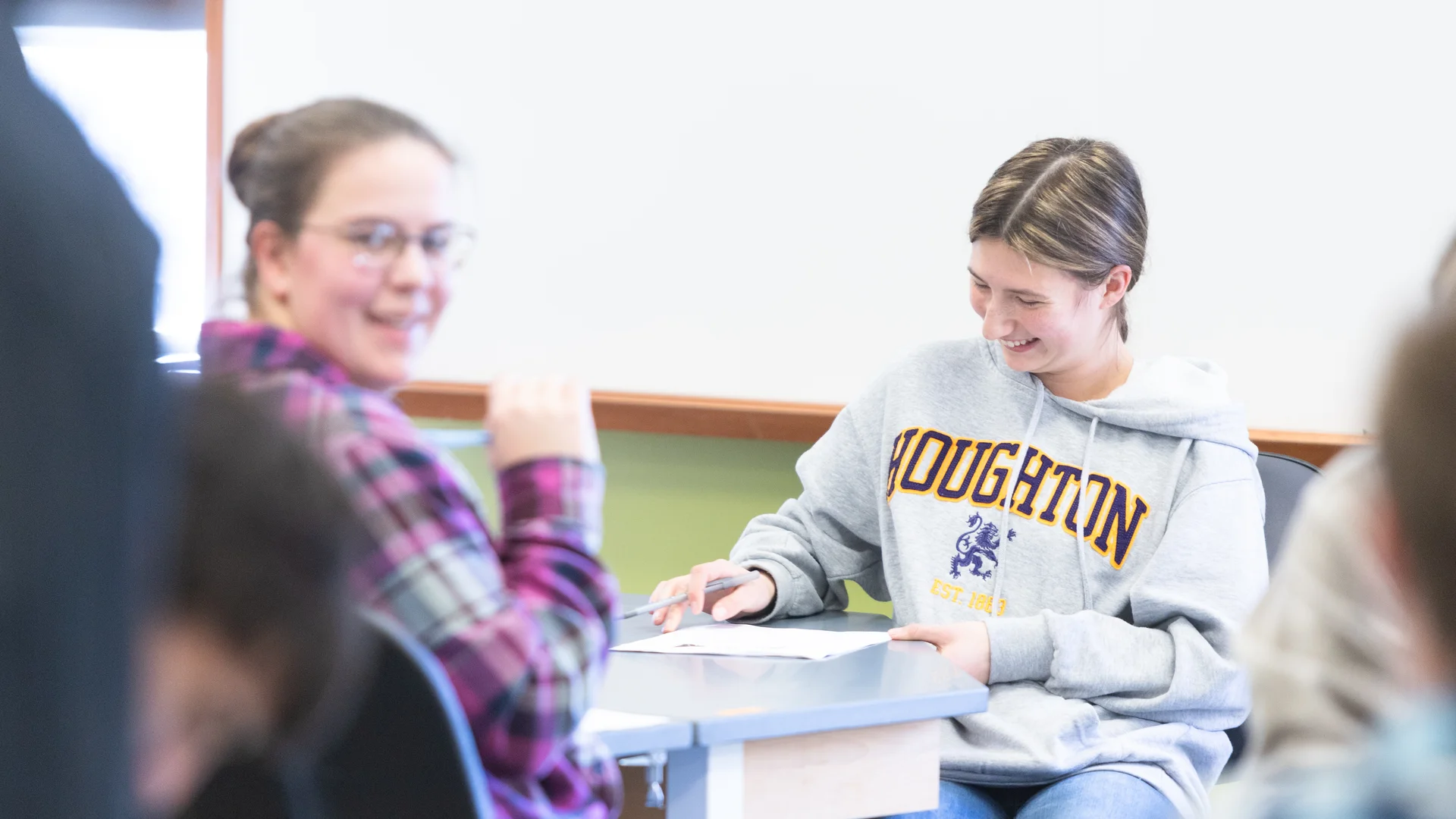 Two Houghton students sitting at lab table during class, one wearing a Houghton sweatshirt.
