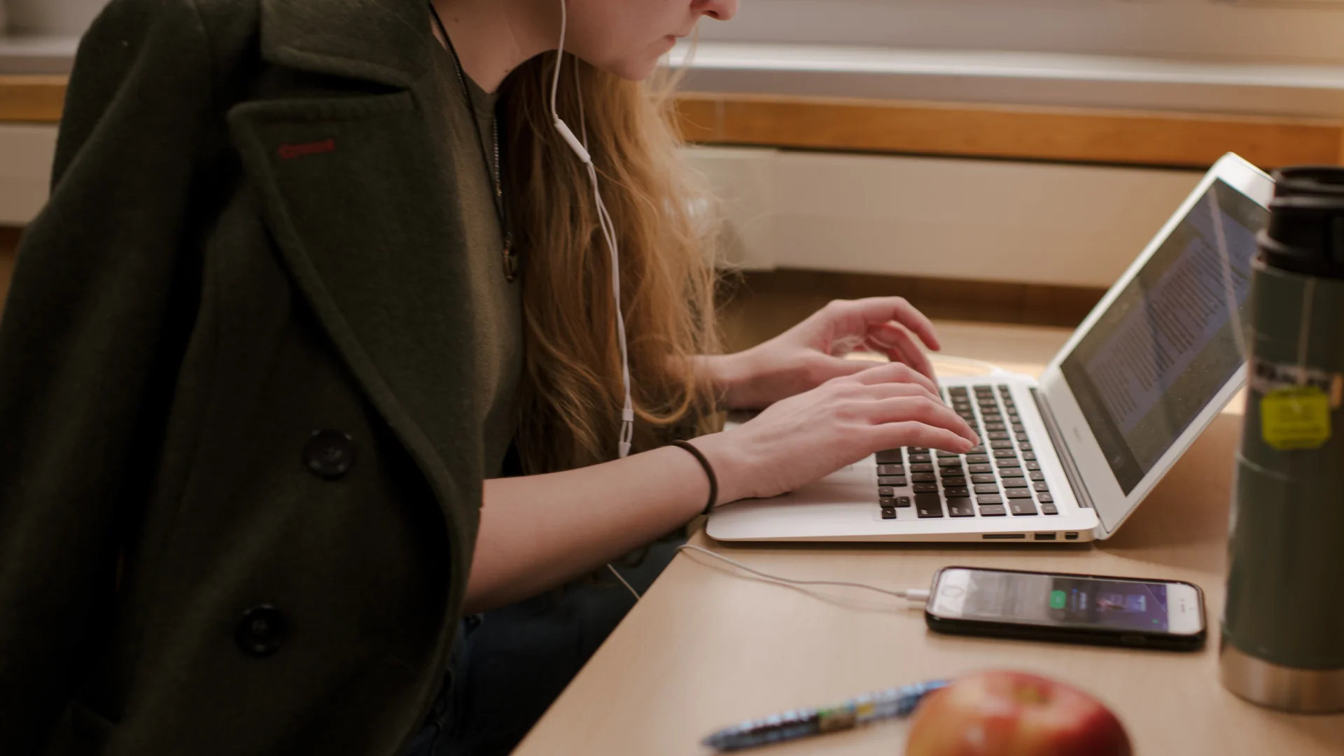 Houghton student typing on laptop in library.