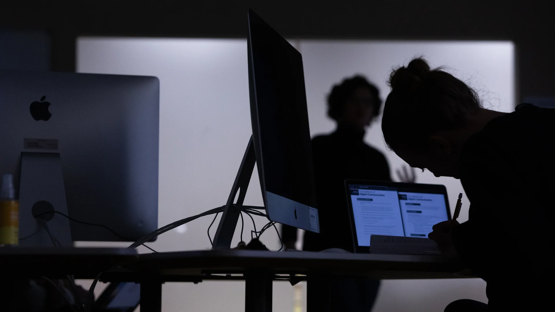 Houghton bfa in graphic design student working in mac lab with dimmed lights during graphic design course.