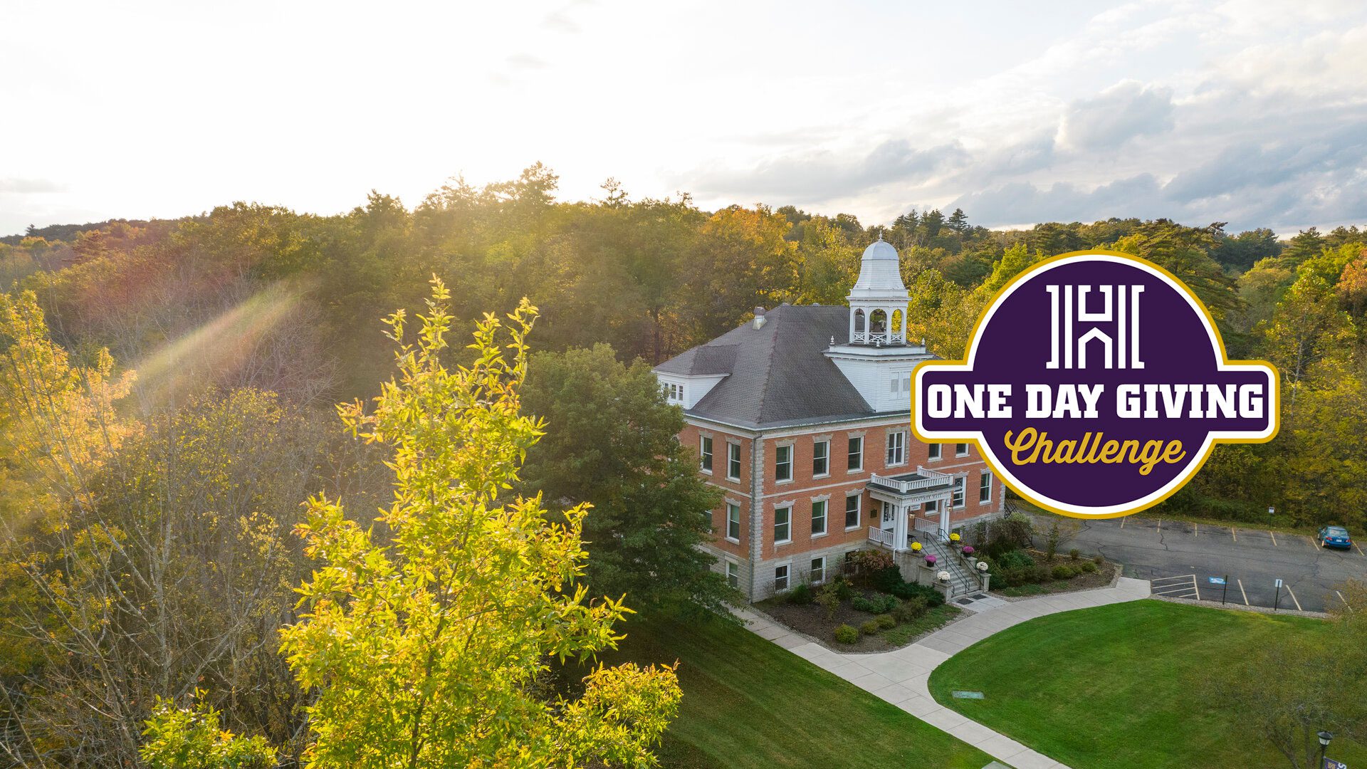 One Day Giving Challenge mark over a photo of Fancher Hall with the sun at the horizon
