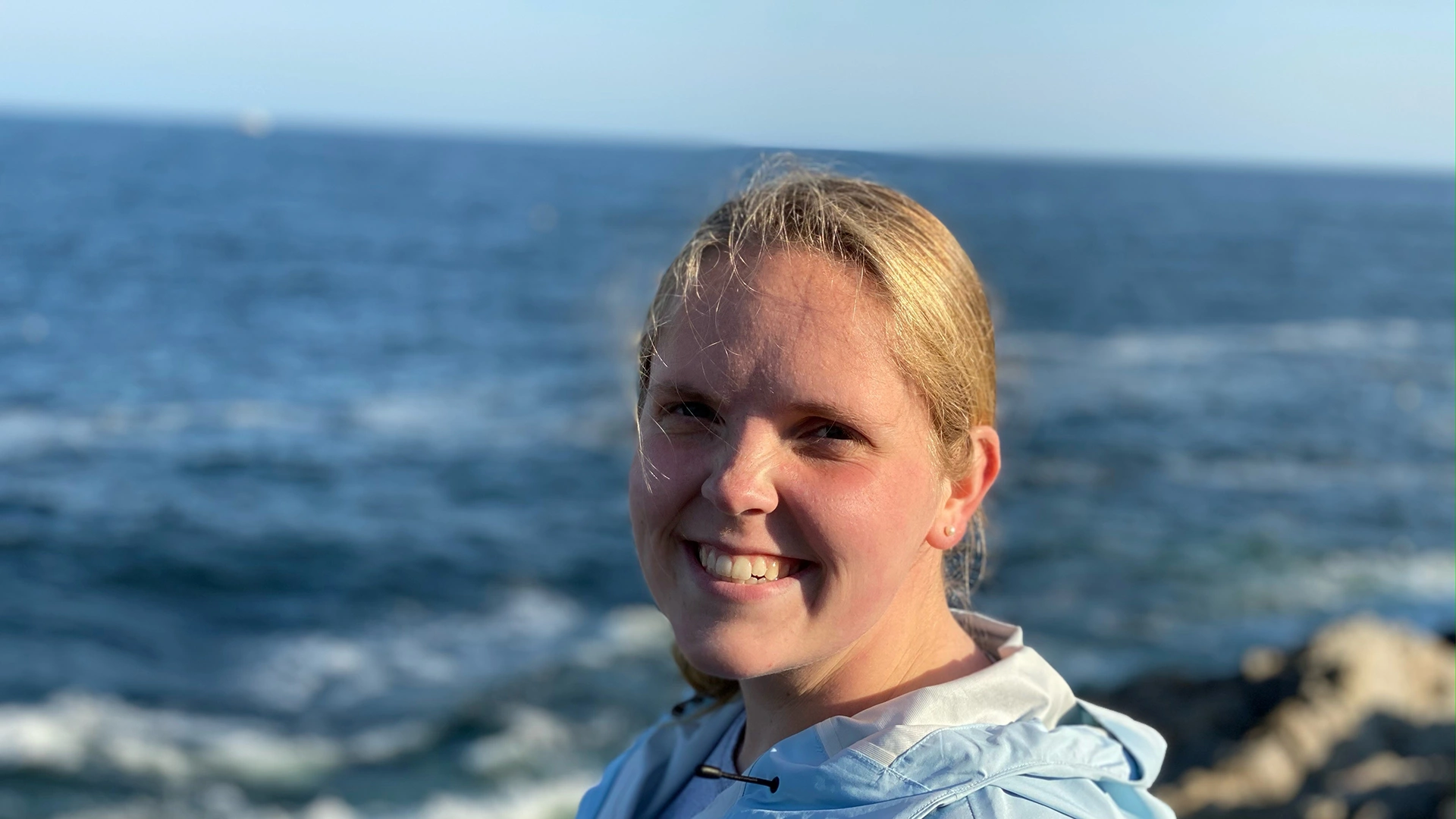 Houghton psychology graduate Tess standing on sea shore.