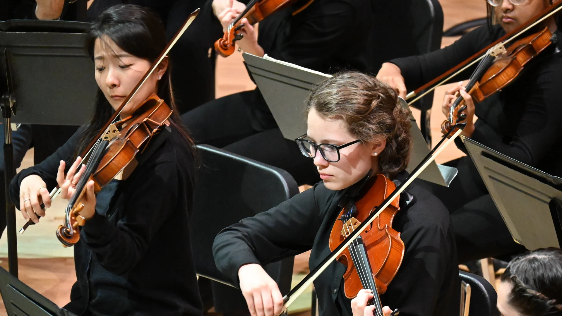 Houghton students playing violins during orchestra performance.