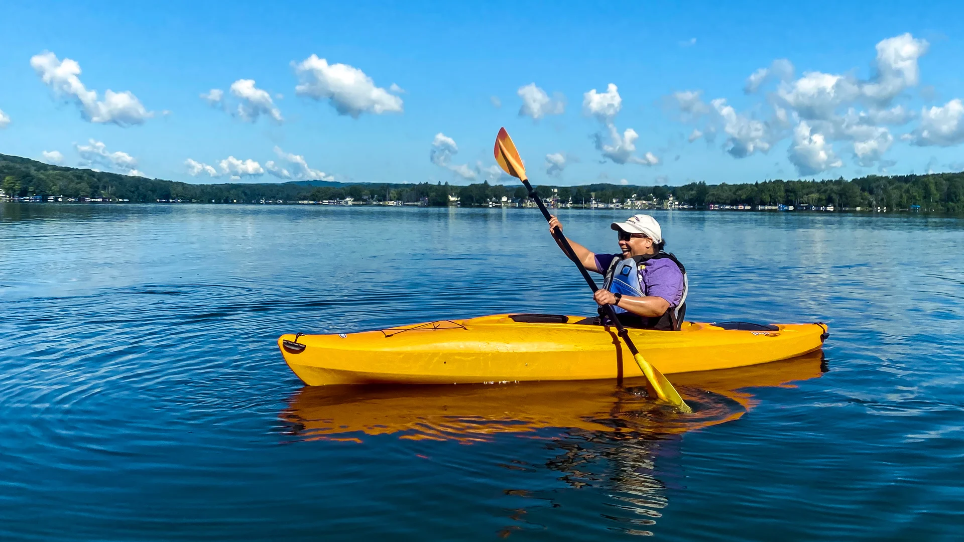 Houghton staff member in kayak paddling on Rushford Lake.