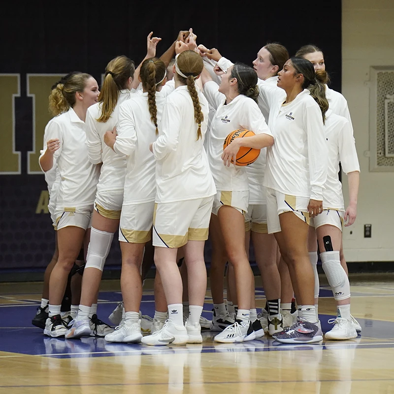 Houghton women's basketball team gathering together in huddle.