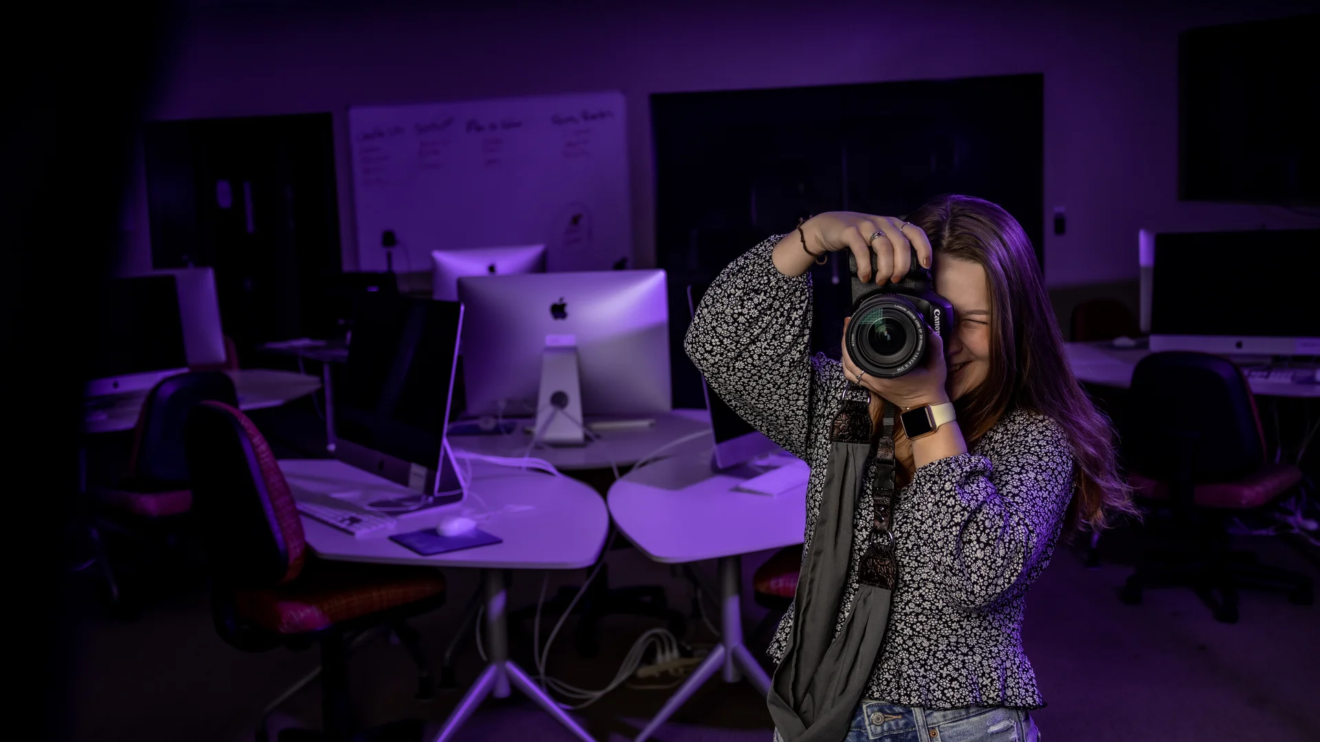 Houghton alumna Rylee taking photos with camera in mac lab.