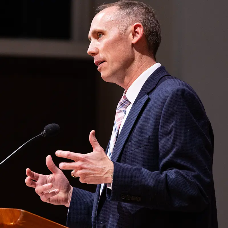 ���Ͽ� JL Miller speaking on the stage of the Chapel.