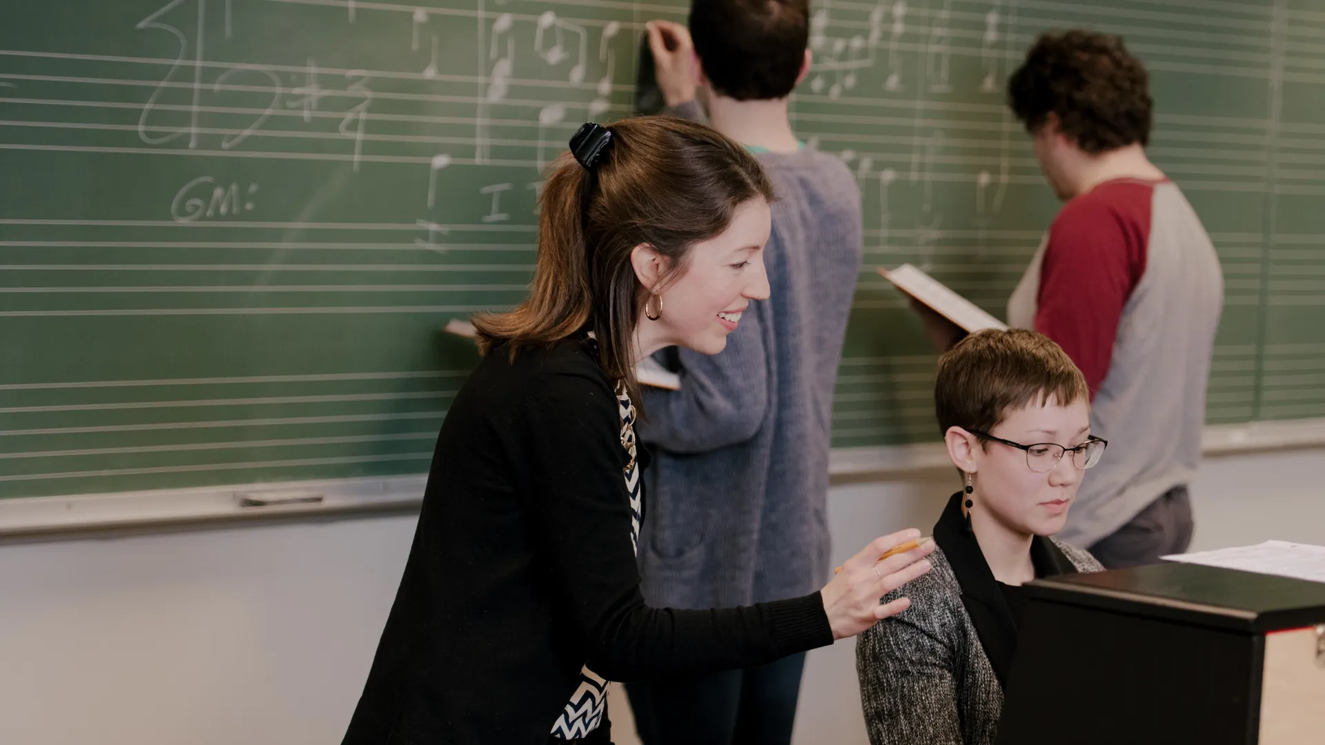 ���Ͽ� Music Teacher in the classroom helping a student with the piano.