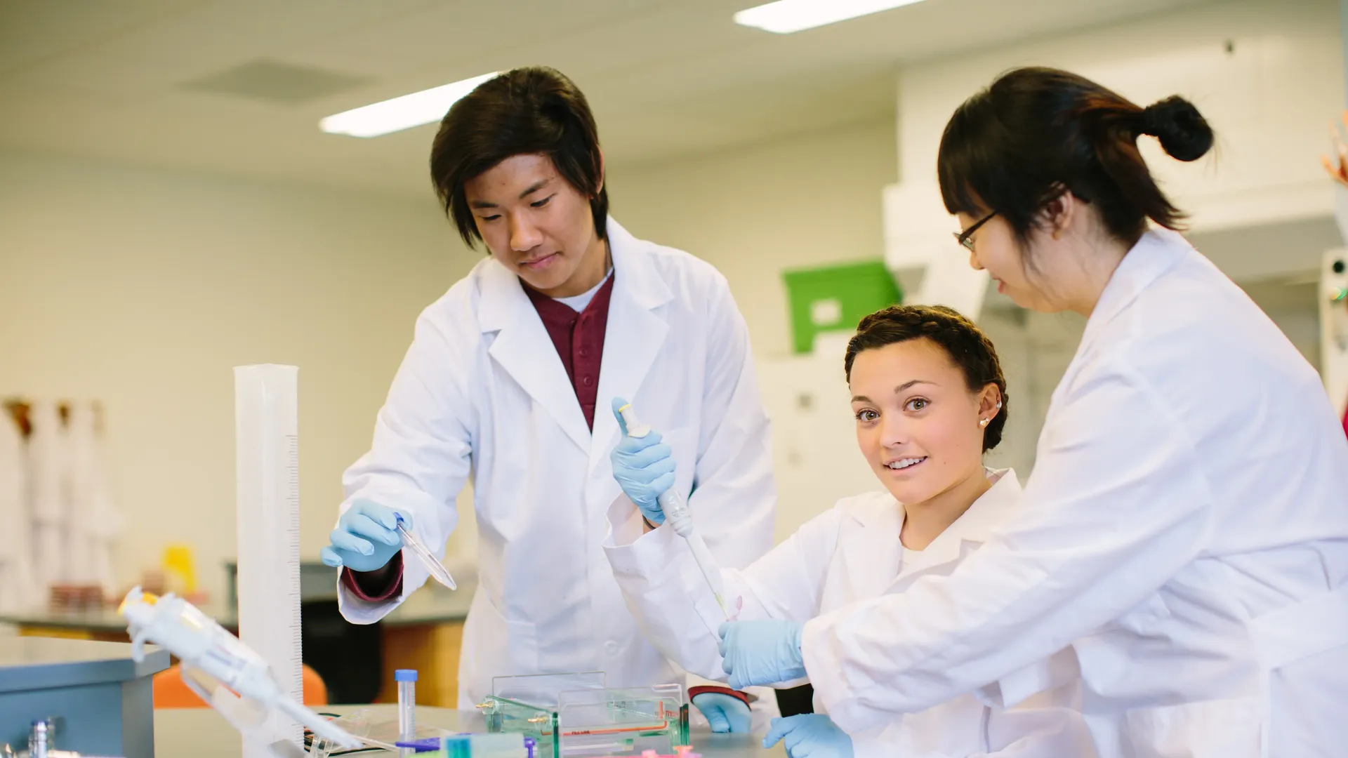 Students working in the lab with vials and lab coats.